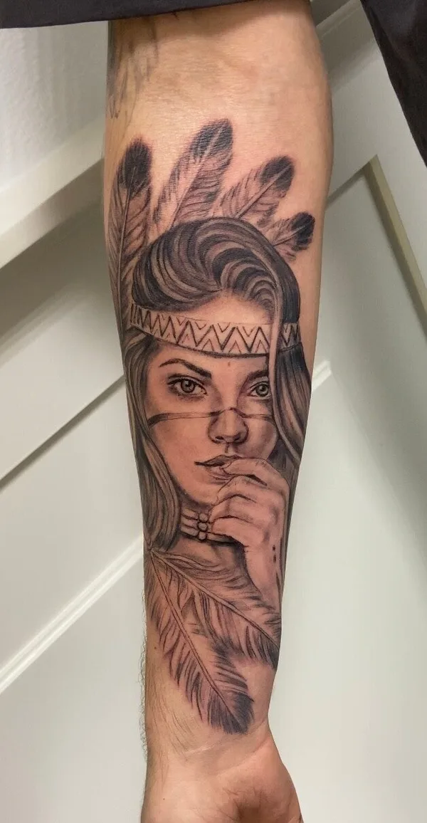 Realistische tattoo van een vrouw met veren op een onderarm, bij Milligan's Tattoo